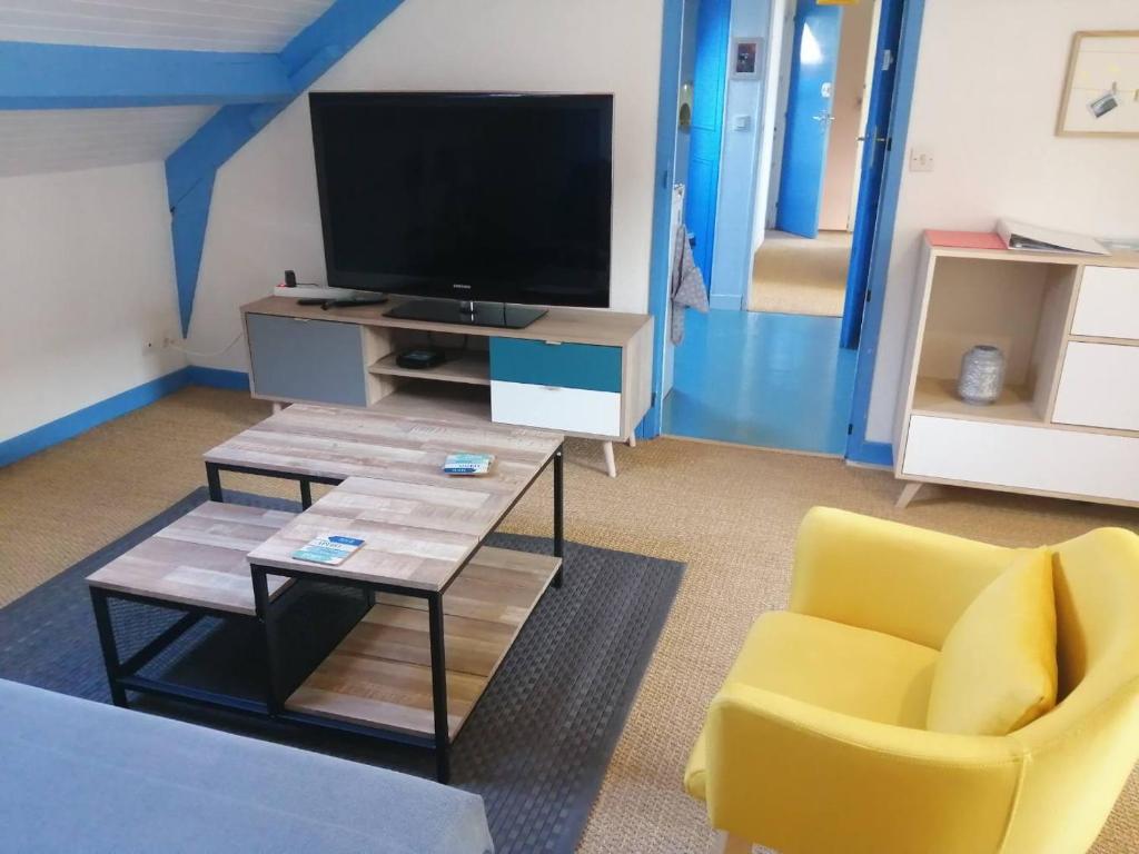 a living room with a tv and a table and a yellow chair at Grand et Charmant 3 pièces Breton Saint Brieuc Centre in Saint-Brieuc