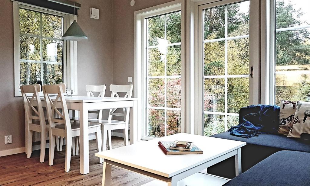un soggiorno con tavolo, sedie e finestre di Nybyggd stuga intill skogsbrynet - New built cottage next to the cowberry forest a Mora