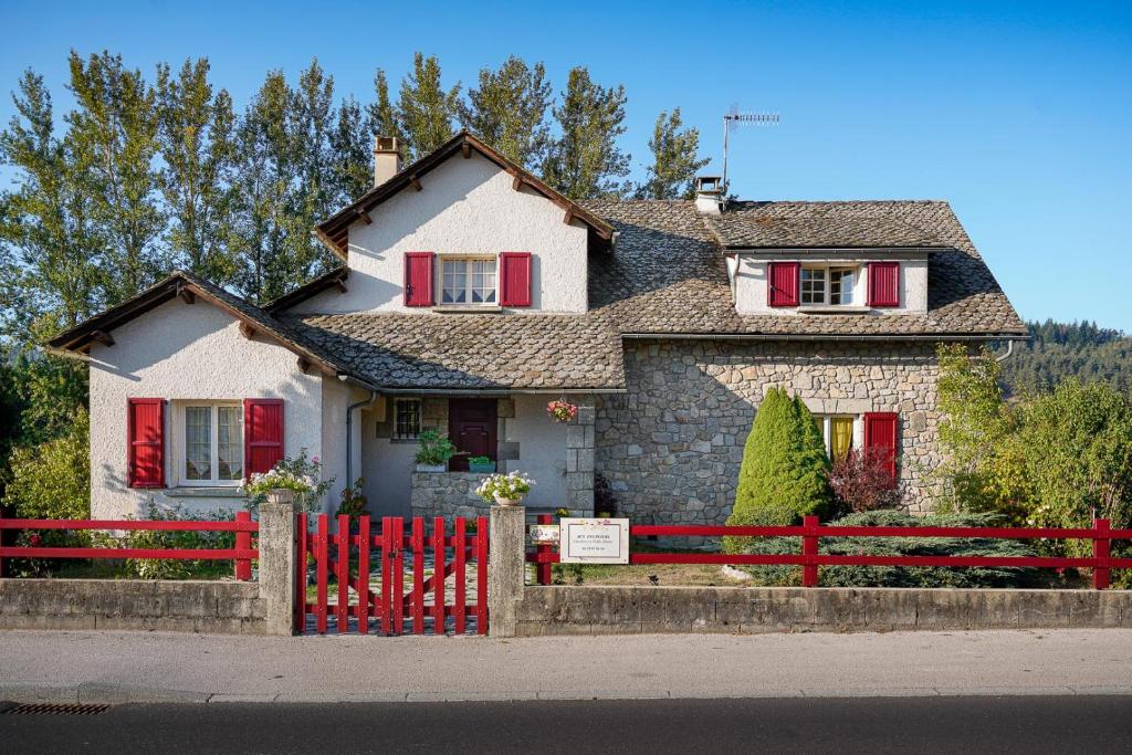 una casa con una valla roja delante de ella en Aux Peupliers, en Le Malzieu-Ville