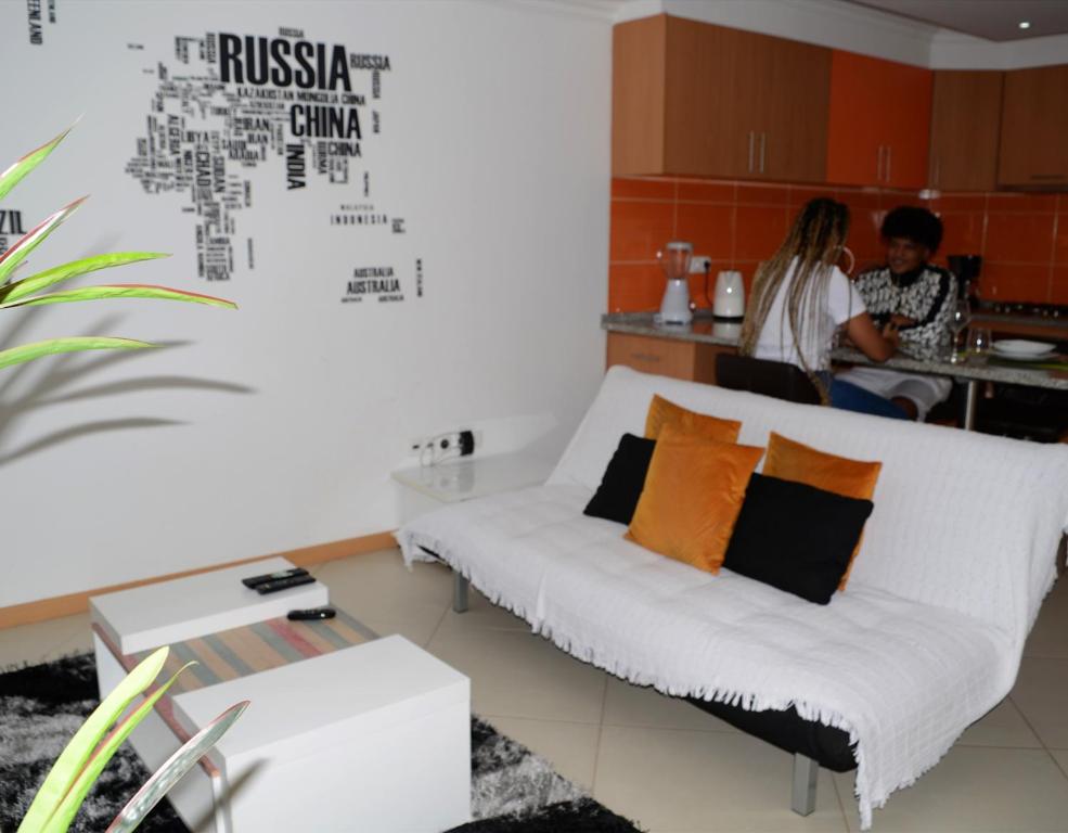 ein Wohnzimmer mit einer Couch und Menschen in der Küche in der Unterkunft Domingas in Praia