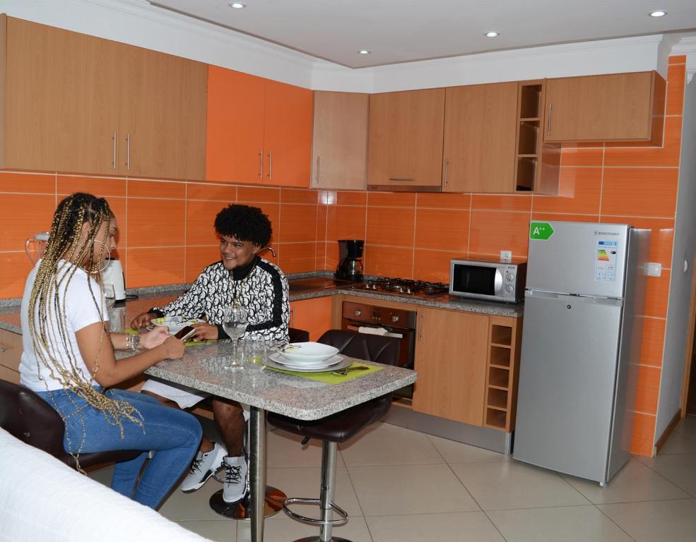 two women sitting at a table in a kitchen at Delux Appartment in Praia