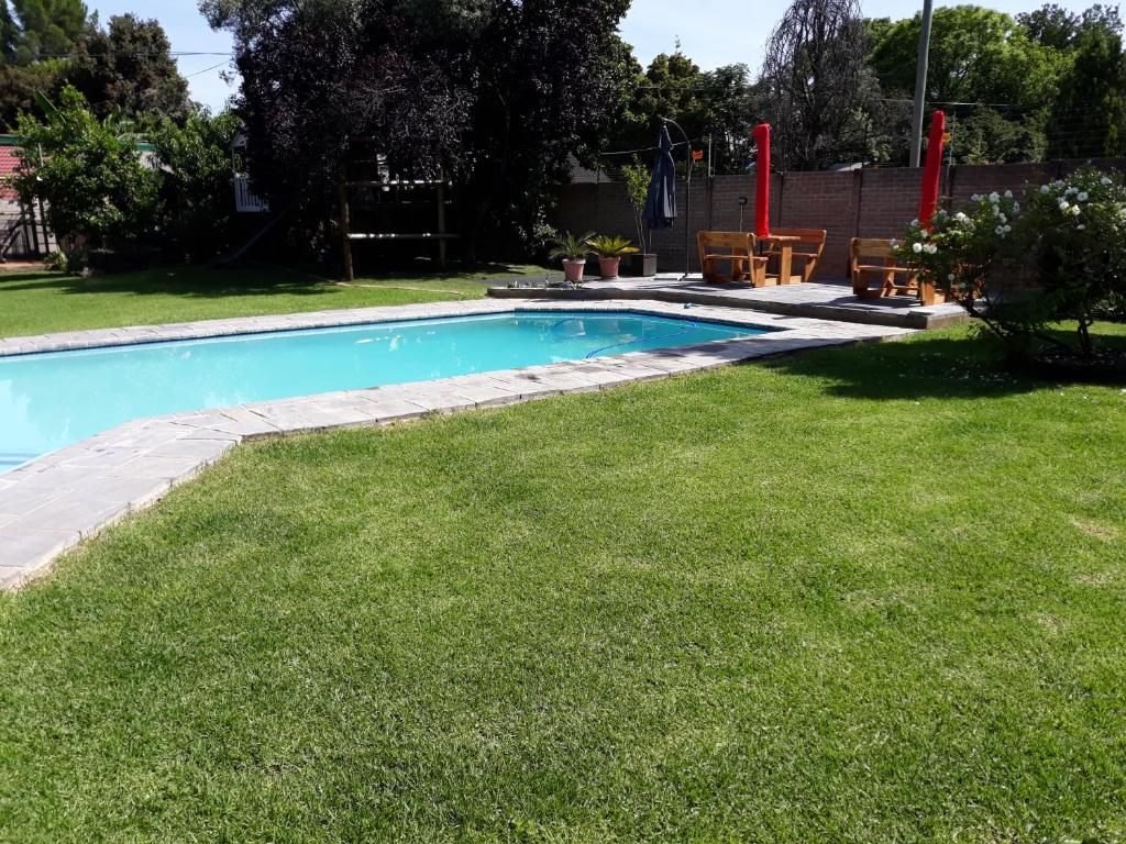 ein Pool in einem Garten mit grünem Gras in der Unterkunft 8 Ibis Lane Guest House in Johannesburg