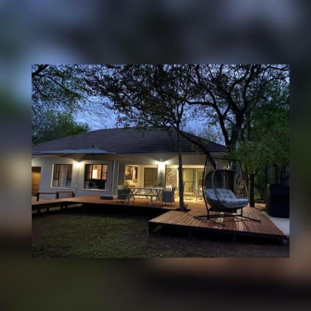 a house with a porch with a chair on a deck at InniBos Marloth Park in Marloth Park