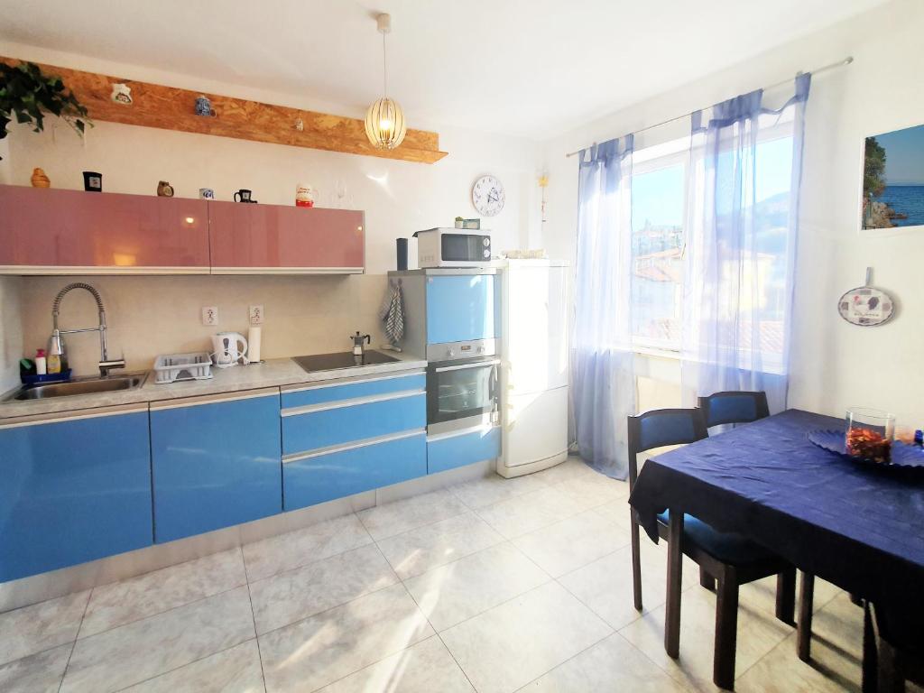 kuchnia z niebieskimi szafkami i stołem w obiekcie Apartmani Senka w mieście Ika