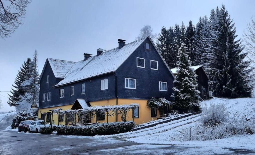een groot zwart en oranje huis met sneeuw erop bij Pension Adolfshaide in Wurzbach