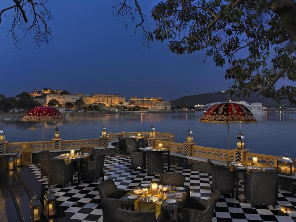 a patio area with tables and chairs and umbrellas at The Leela Palace Udaipur in Udaipur