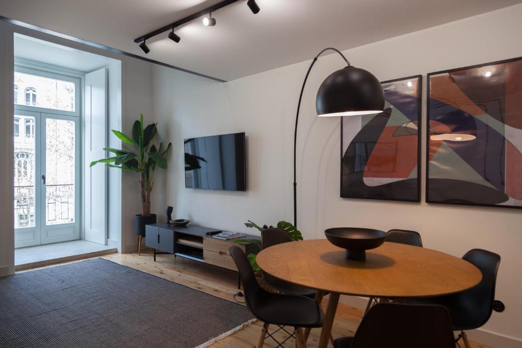 a living room with a table and chairs and a tv at FLH Intendente Industrial Design Duplex in Lisbon