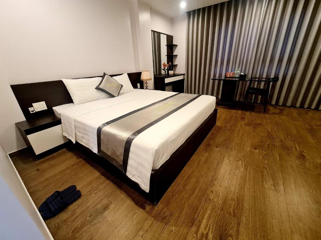 een slaapkamer met een groot bed en houten vloeren bij Novatel Hotel & Apartment in Hai Phong