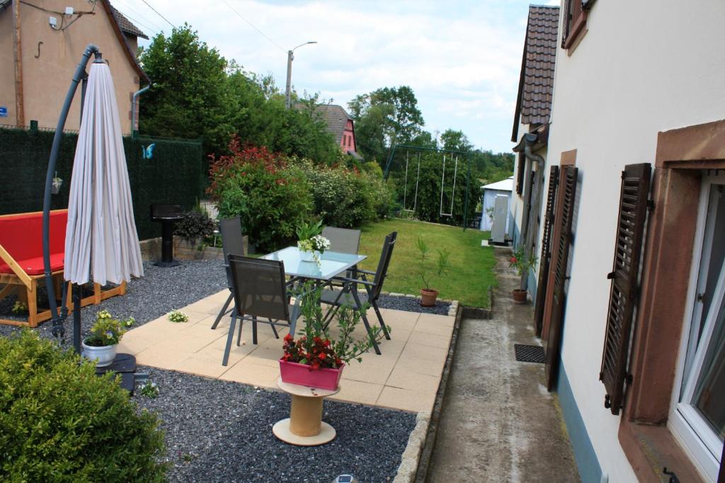 un patio avec une table, des chaises et un parasol dans l'établissement Maison charmante à Gottenhouse + Jardin, à Gottenhouse
