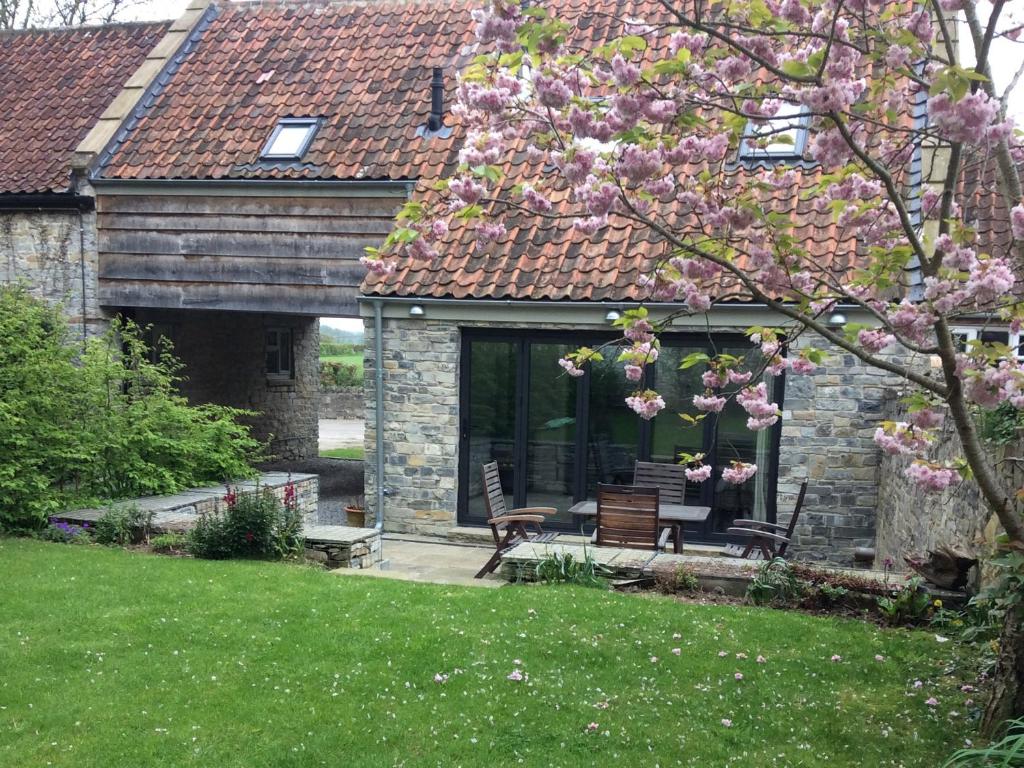 a house with a bench and a tree with pink flowers at Willow Barn in Bridgwater
