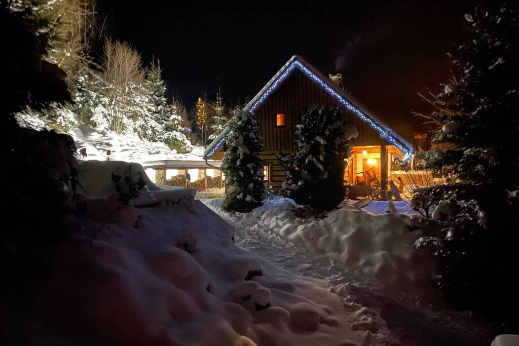 uma cabana na neve à noite em Wooden house in the heart of the Giant Mountains with own hill em Víchová nad Jizerou