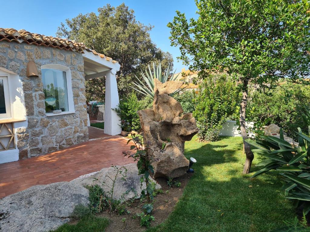 un jardín con una casa de piedra y un árbol en Casa Mariu' ,con giardino vista mare, en Liscia di Vacca