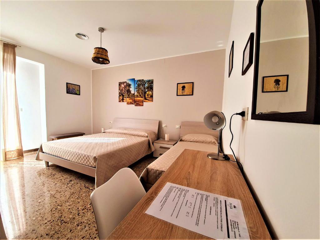 1 dormitorio con 2 camas y mesa con escritorio en Paisà B&B, en Crispiano
