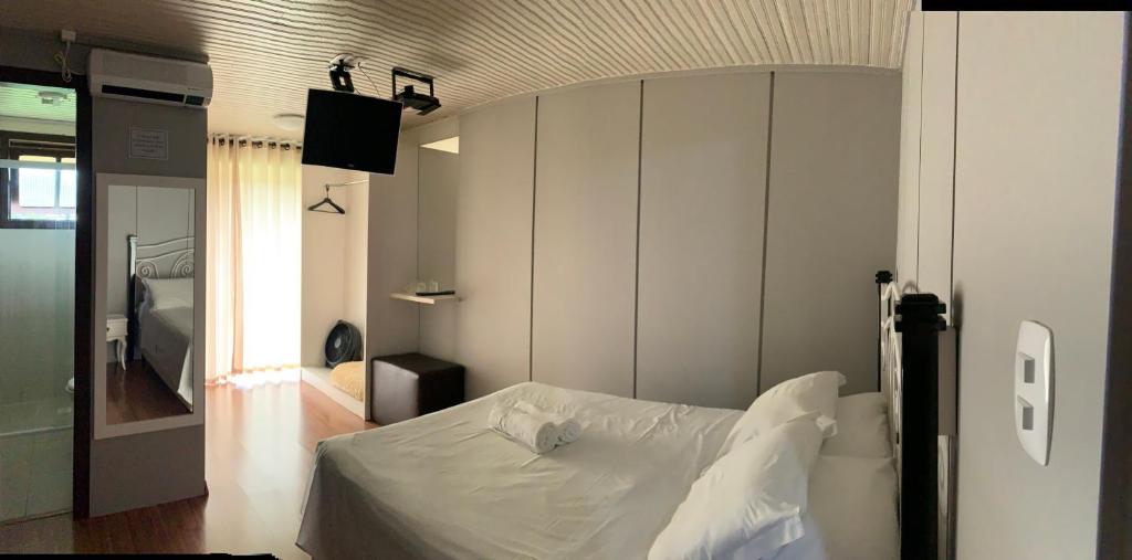 1 dormitorio con 1 cama blanca en una habitación en Hotel Morada dos Pinheiros, en Bom Jardim da Serra