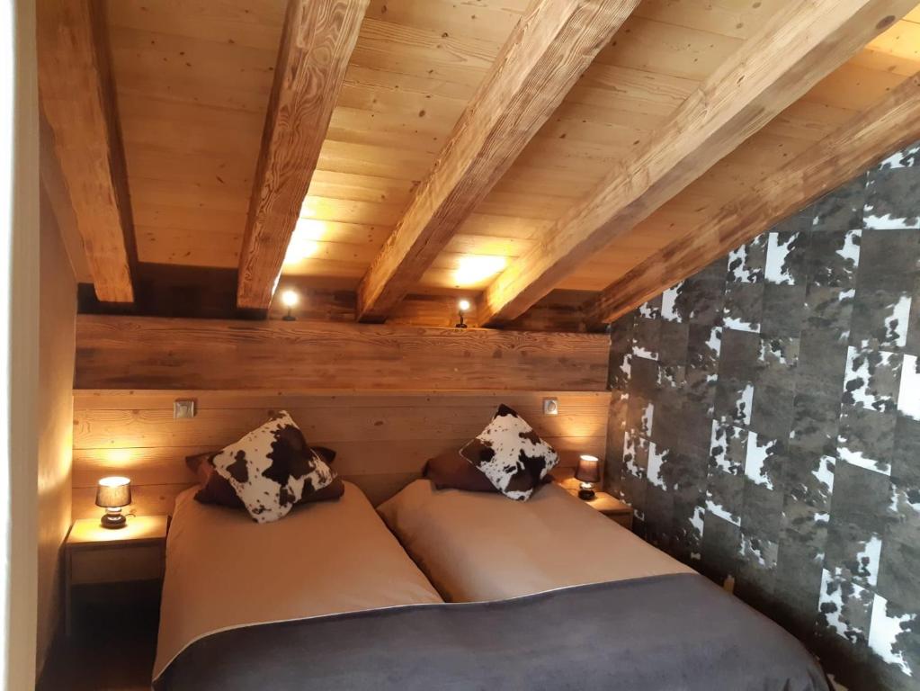 two beds in a room with wooden walls at Chalet Emilie in Courchevel