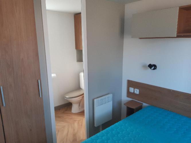 a room with a bed and a bathroom with a toilet at Les dunes de contis in Saint-Julien-en-Born