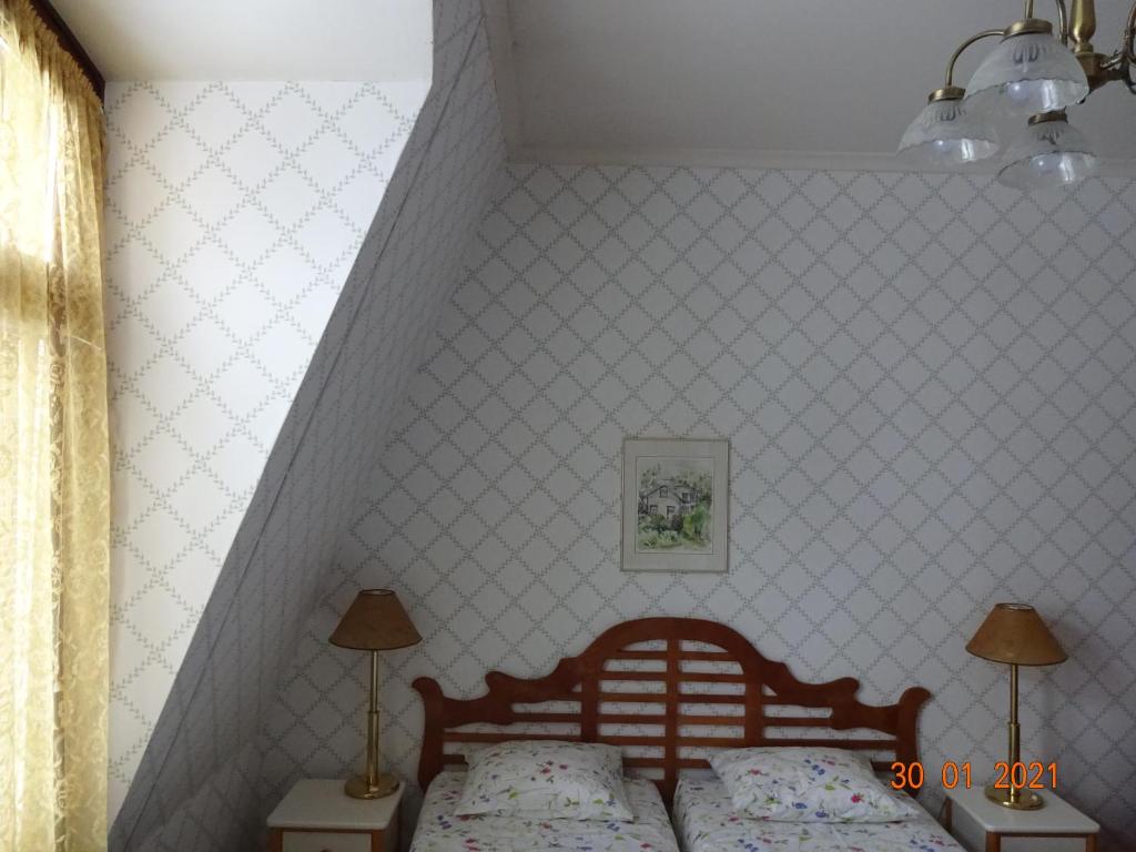 a bedroom with a bed and two lamps and a wall at Mäntyluodon Hotelli in Pori