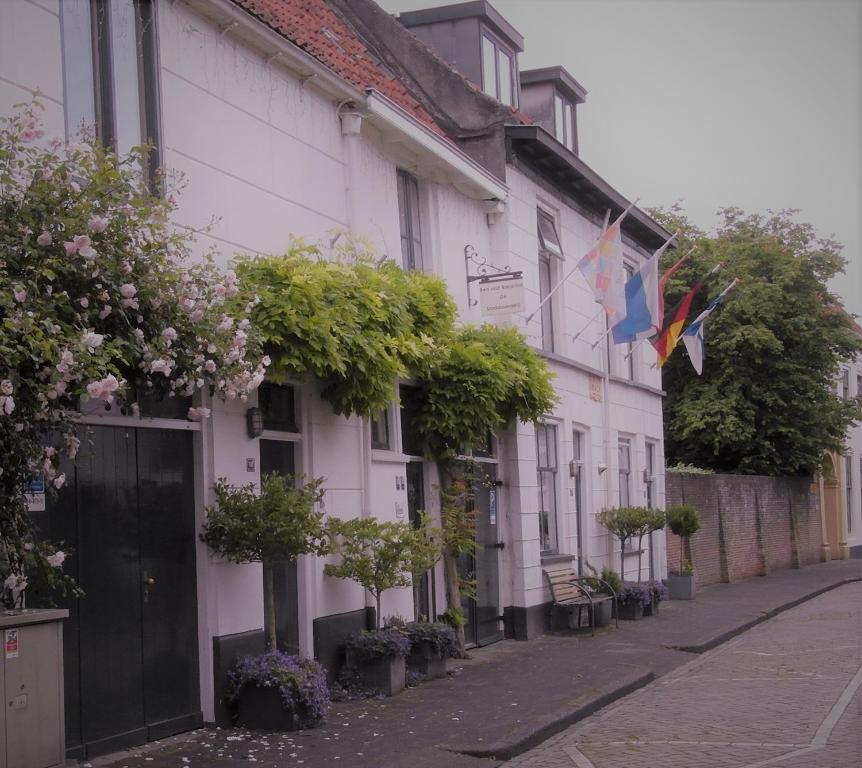 a white building with flags on a street at De Stadsboerderij in Kampen