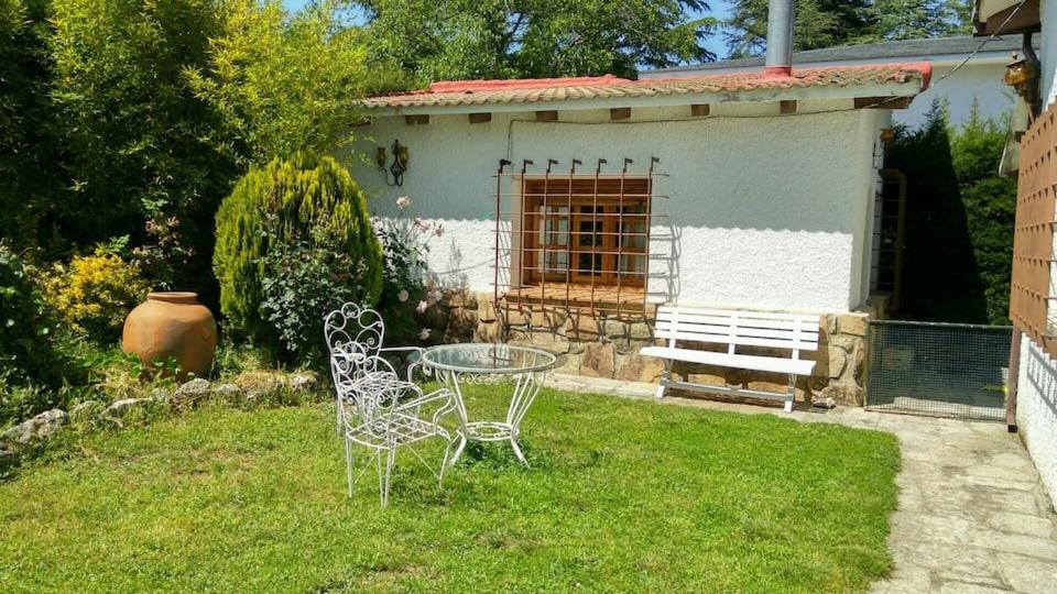 a table and two chairs in a yard with a house at La Casita de Chozas in Soto del Real