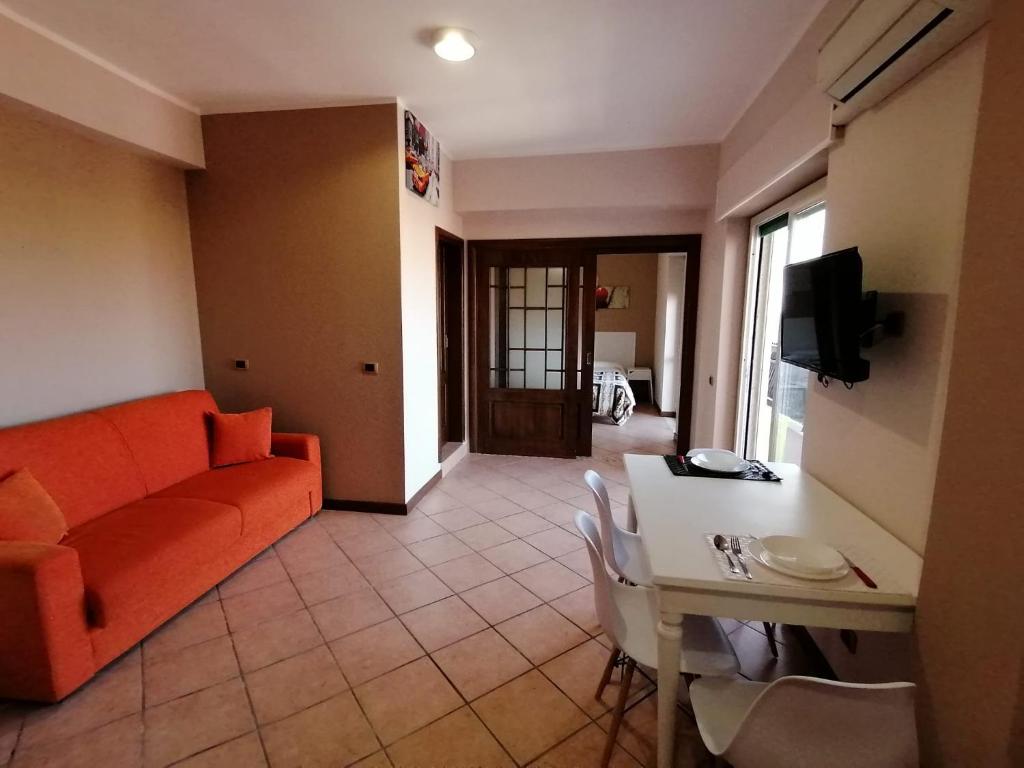 a living room with an orange couch and a table at LAMEZIA AIRPORT APPARTMENT. in SantʼEufemia Lamezia