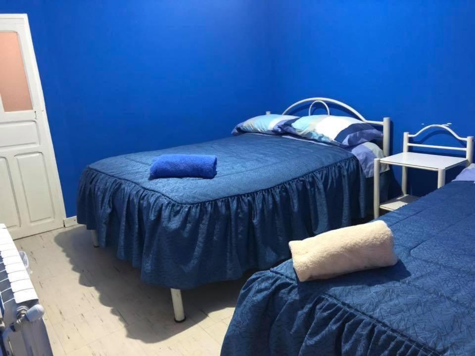 een blauwe kamer met 2 bedden en blauwe muren bij Hostal CASABLANCA in Oruro