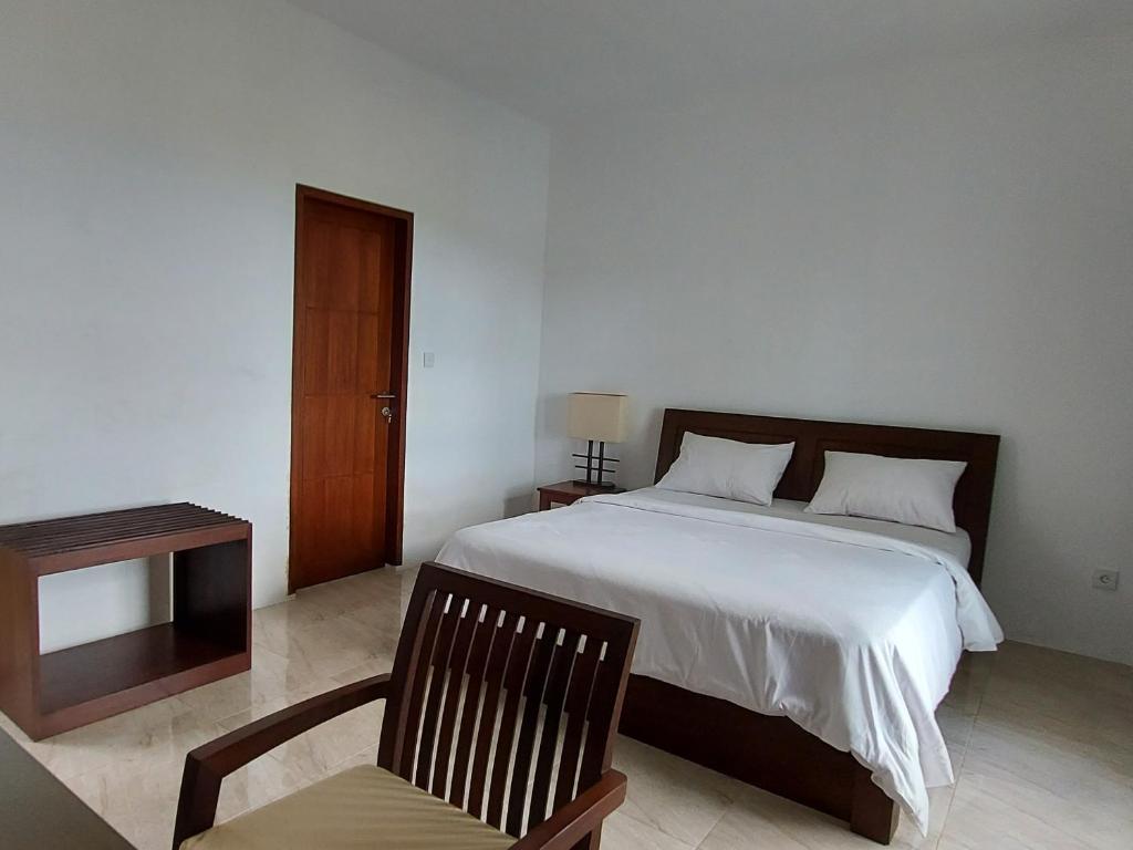 a bedroom with a bed and a chair and a table at Villa Aryaguna in Senggigi 