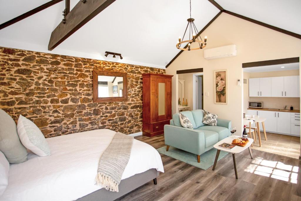 a bedroom with a brick wall and a bed and a couch at Settlers Cottage in McLaren Vale