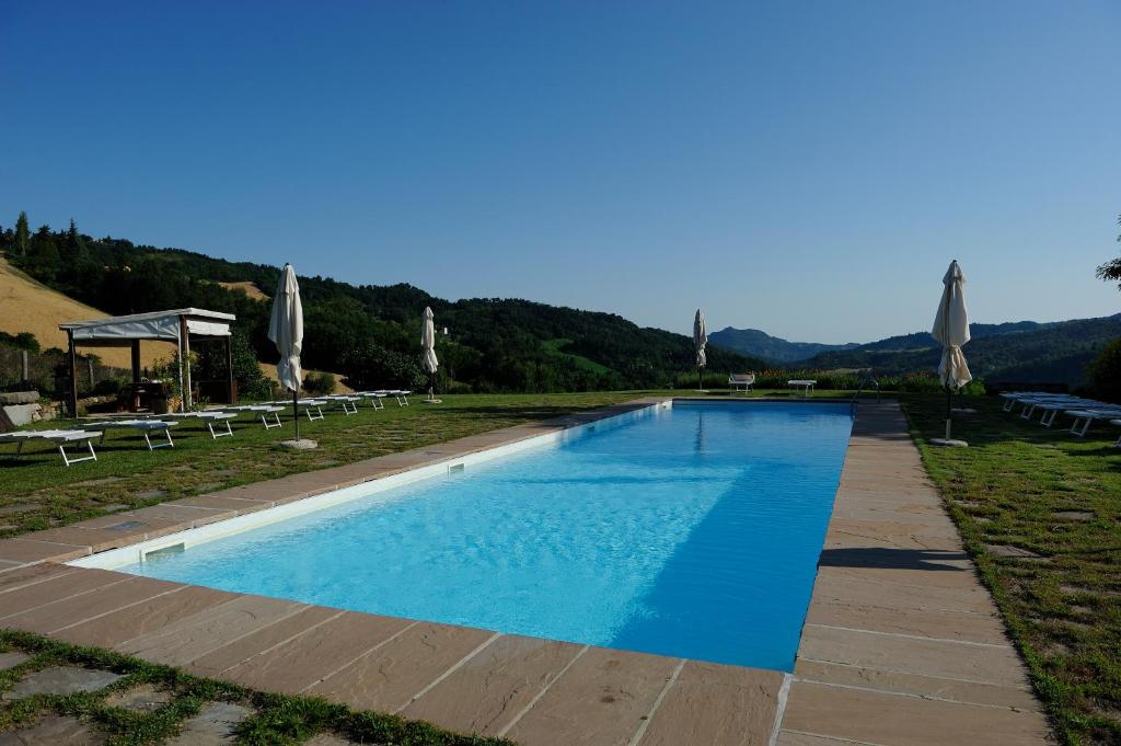 a large swimming pool with umbrellas and chairs at Lodole B&B in Monzuno