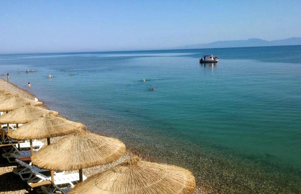 a beach with umbrellas and a boat in the water at Castella Beach in Alissos