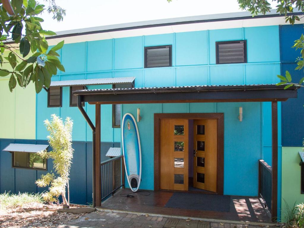 a blue building with a door and a surfboard on it at Colours of Cylinder in Point Lookout