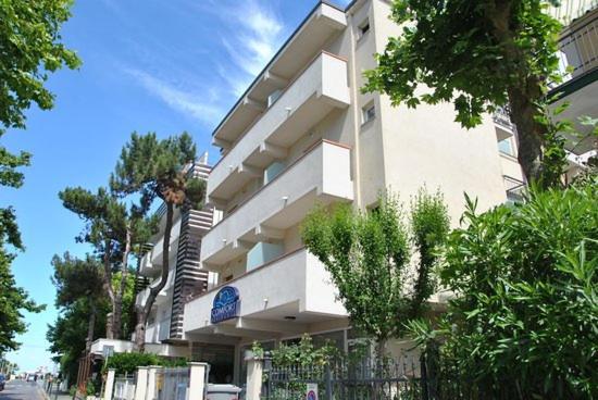 un gran edificio blanco con plantas delante en Residence Comfort, en Riccione