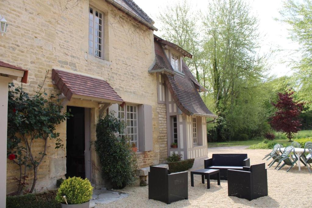 uma casa com um pátio, uma mesa e cadeiras em Le vieux moulin em Thaon