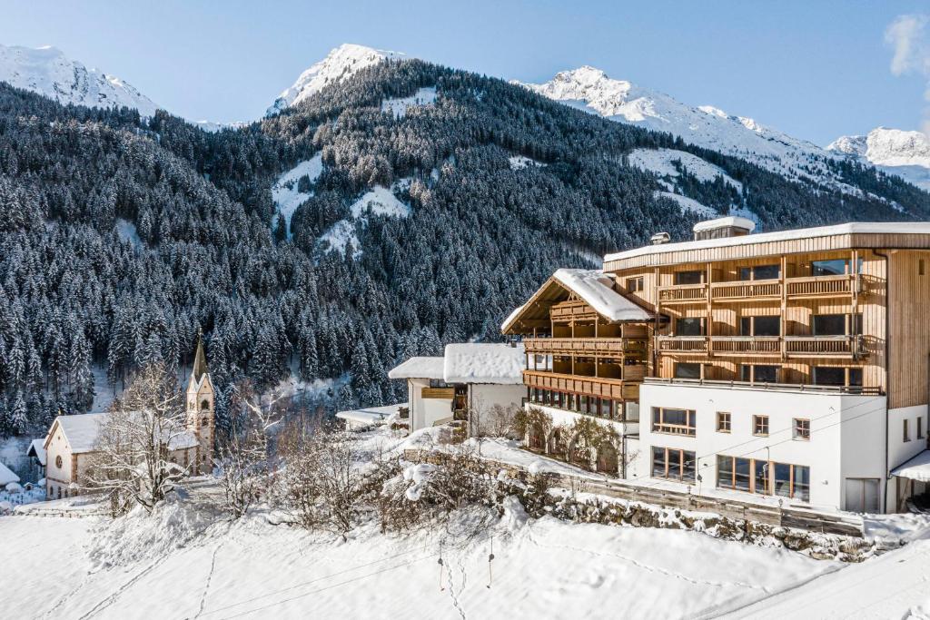 a hotel in the snow with mountains in the background at Hotel Panorama in Fleres