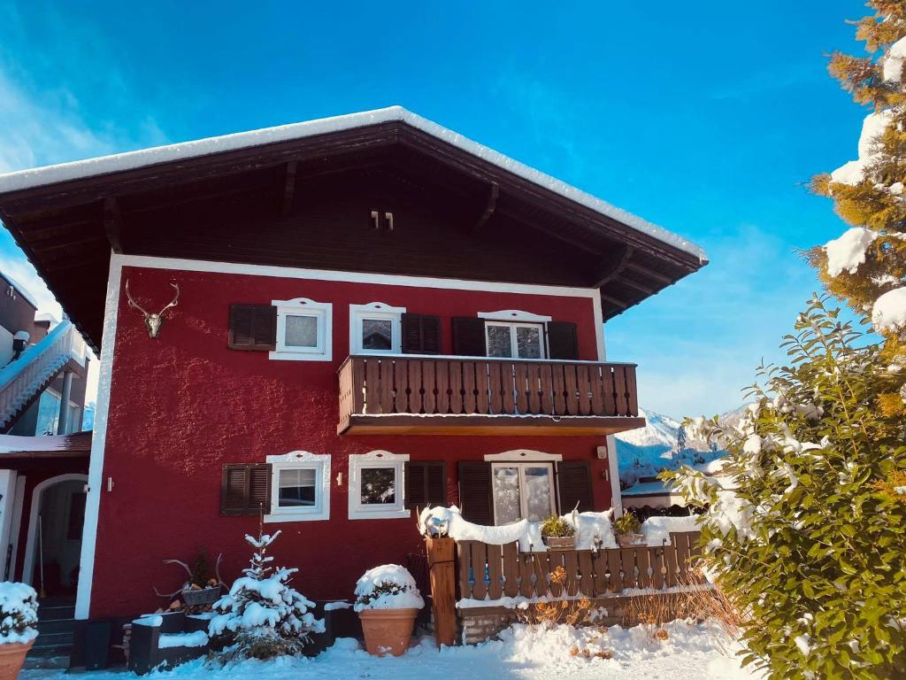a red house with a balcony in the snow at Hunter's Chalet, up to 10 p, terrace with amazing mountainview, 200 qm garden, BBQ&bikes&sunbeds for free in Golling an der Salzach