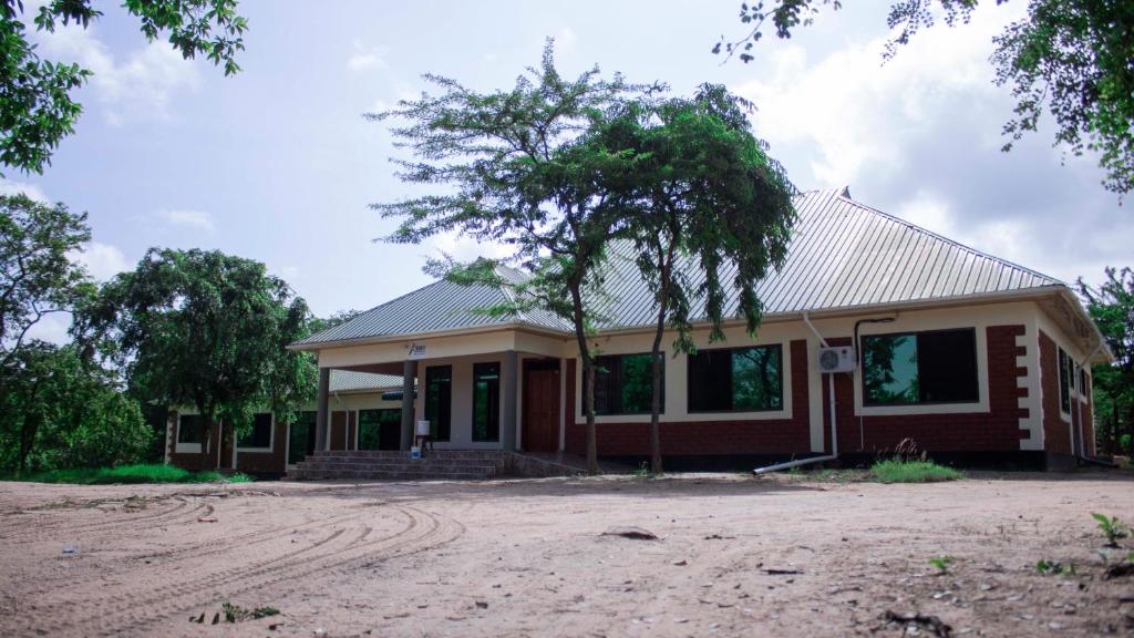 a house with a tree in front of it at MANTIS LODGE & CAMPING SITE in Morogoro