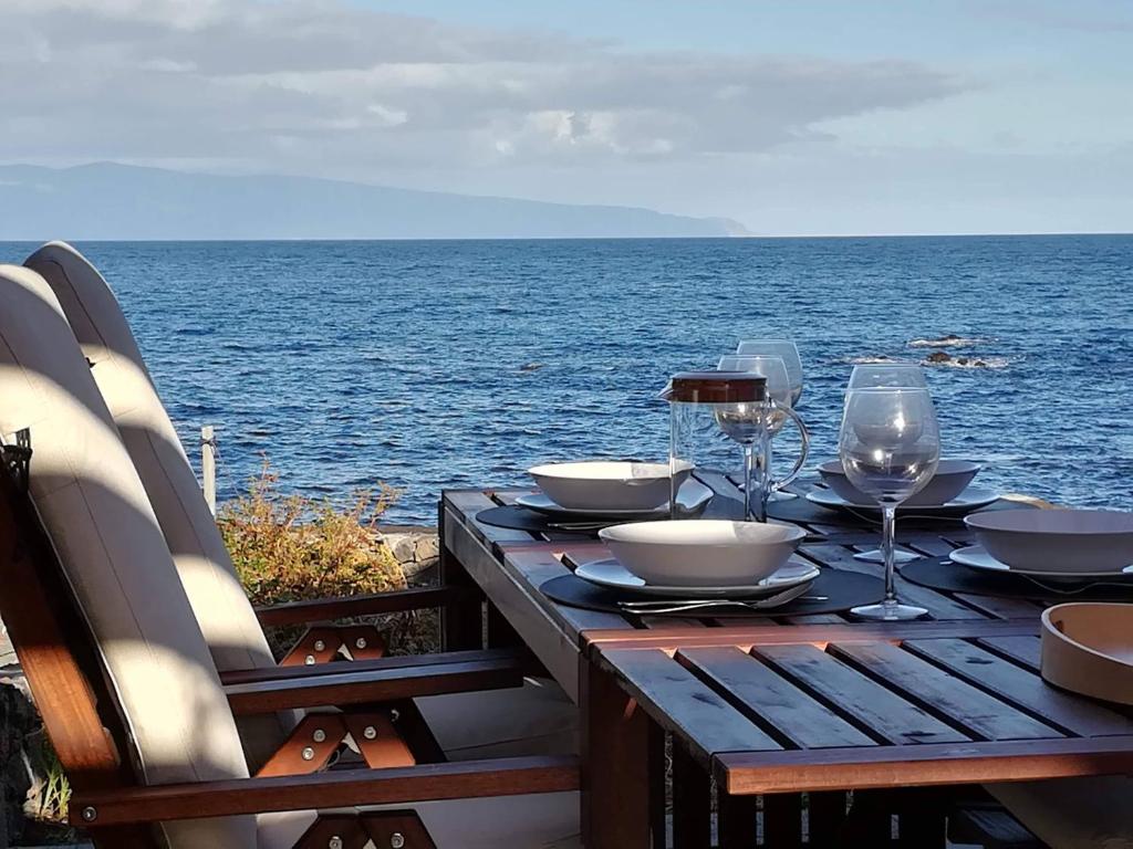 - une table en bois avec des verres à vin et une vue sur l'océan dans l'établissement Janela do Porto, à Prainha de Baixo