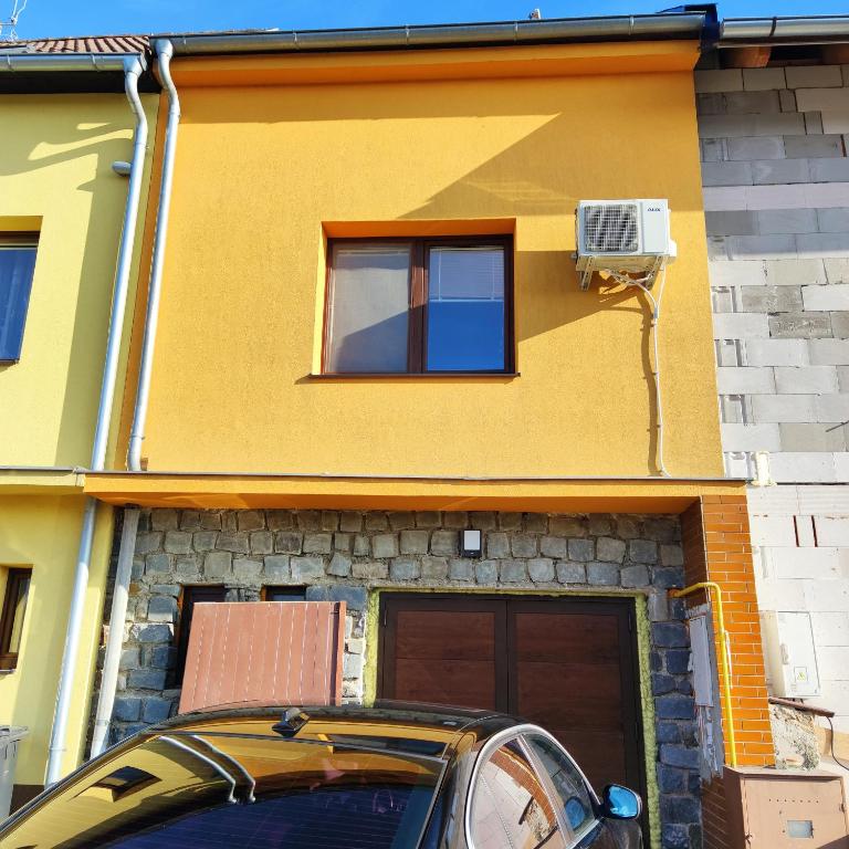 ein Auto, das vor einem gelben Haus parkt in der Unterkunft Ubytování na sklepě u ŠPACÍRA in Velké Pavlovice