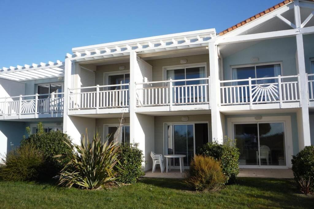 - un bâtiment blanc avec un balcon et une table dans l'établissement T2 Résidence avec piscine chauffée de mai à sept, à Saint-Jean-dʼOrbetiers
