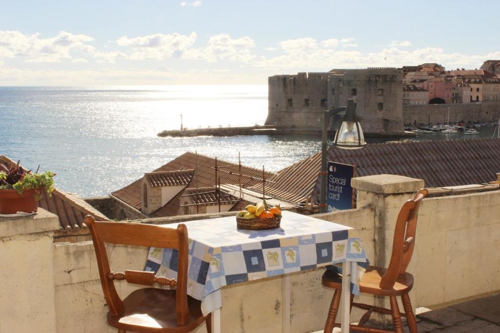 a table and chairs on a balcony with a view of the ocean at Rooms Lazareti in Dubrovnik