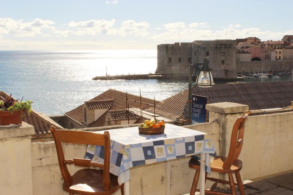 una mesa y sillas en un balcón con vistas al océano en Rooms Lazareti, en Dubrovnik