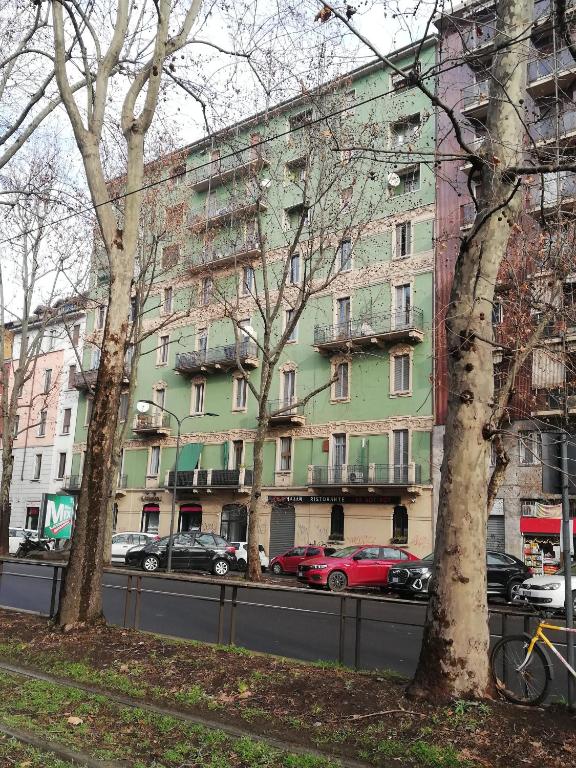 zielony budynek z samochodami zaparkowanymi przed nim w obiekcie Al 32 Apartment w Mediolanie