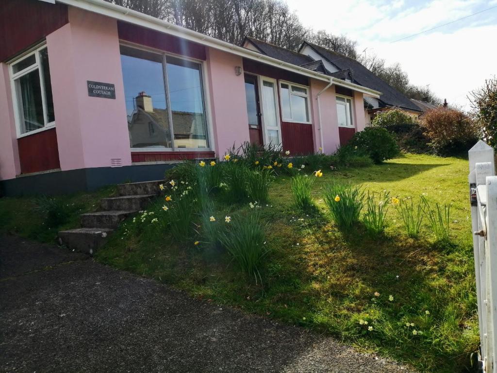 a house with flowers in the front yard at Coldstream Cottage in Dale
