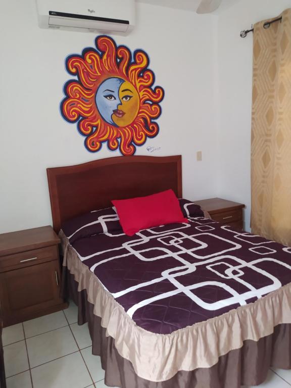 a bed with a painting of the sun on the wall at Bungalows Lulu in Bucerías