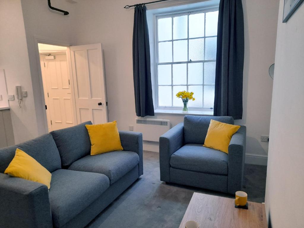 a living room with two blue couches and a window at Eastgate Hideaway - central, luxury apartment on Chester's historic rows in Chester