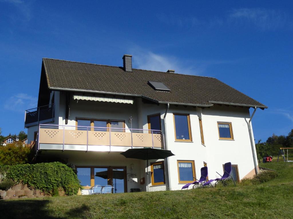 a large white house with a balcony and two chairs at Ferienwohnung An der Traumschleife in Horath