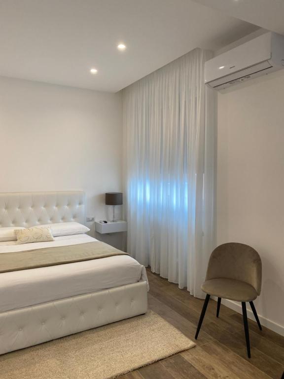 een witte slaapkamer met een bed en een stoel bij B&B La maison foggia in Foggia