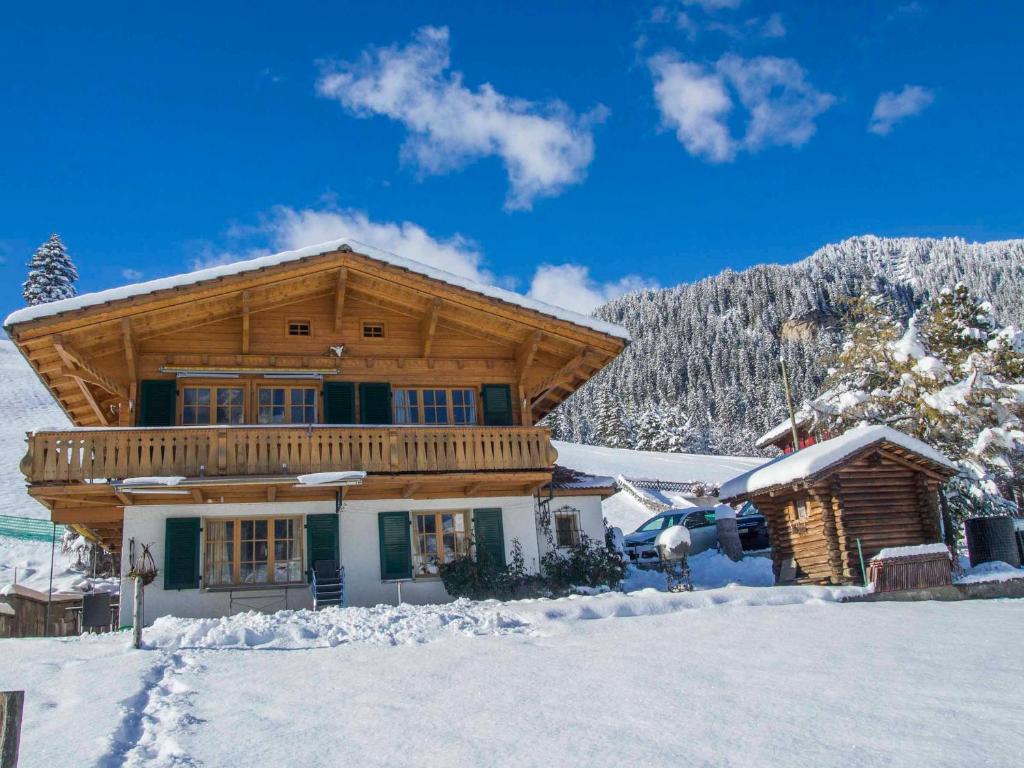 a log cabin in the snow with a car parked in front at Ferienwohnung Chalet Zwirbeli in Adelboden