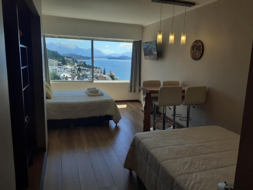 a room with two beds and a large window at Bariloche Home Suites in San Carlos de Bariloche