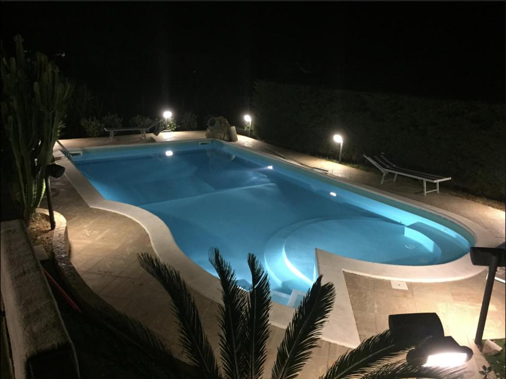 a swimming pool at night with a bench next to it at Villa indipendente in Altavilla Milicia