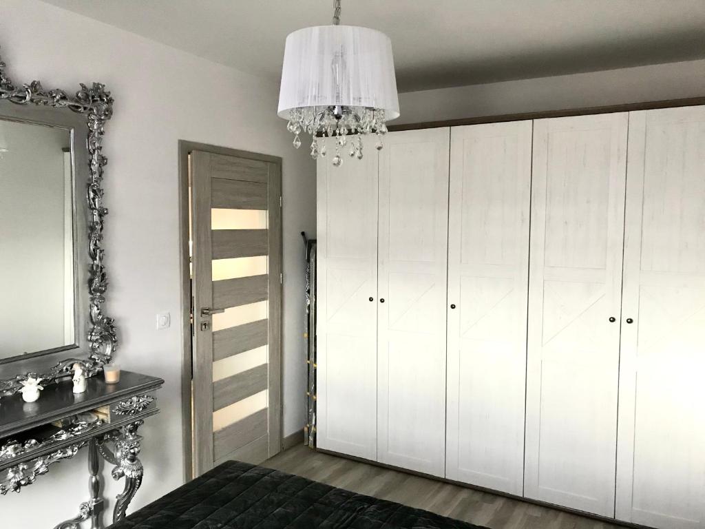 Apartament na Skrzypka في تشيشين: غرفة نوم بها دواليب بيضاء ومرآة